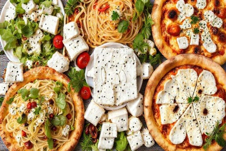 Arranjo artístico de pratos com queijo feta incluindo saladas, massas e pizzas.
