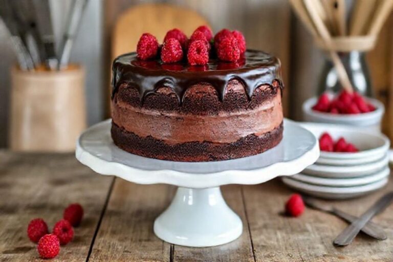 Bolo de chocolate sem glúten decorado com ganache e framboesas.