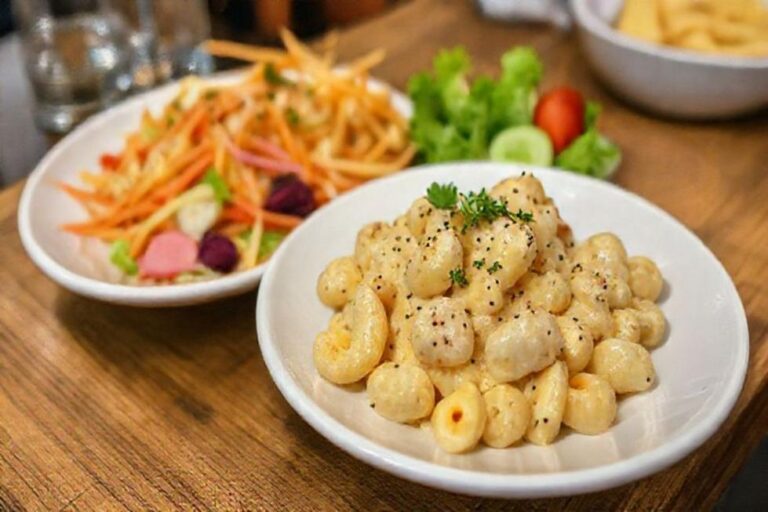Mesa posta com macarrão cremoso e saladas.